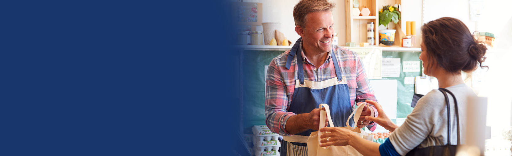  sales assistant serving female customer at checkout of organic farm shop