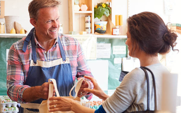  sales assistant serving female customer at checkout of organic farm shop