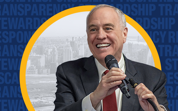 New York State Comptroller Thomas P. DiNapoli holding a microphone and smiling.