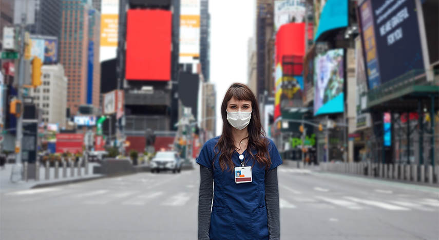 new york city healthcare worker standing in times square wearing hospital uniform and a mask