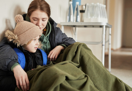 parent and child sitting on floor, covered in a blanket