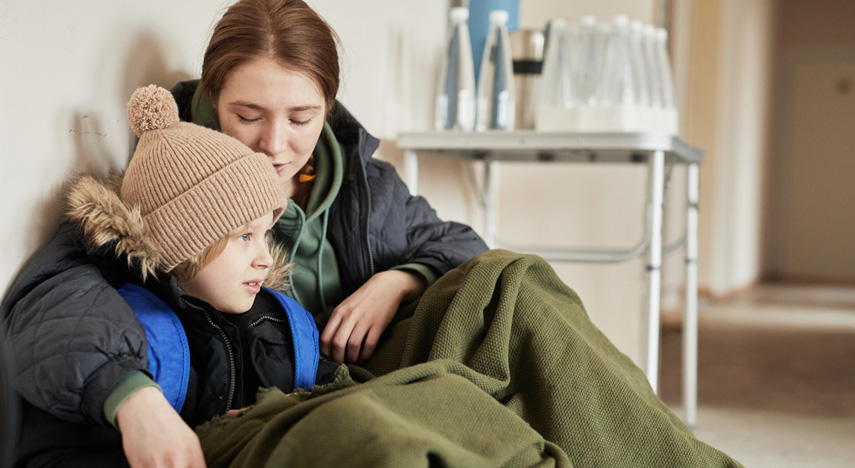 parent and child sitting on floor, covered in a blanket